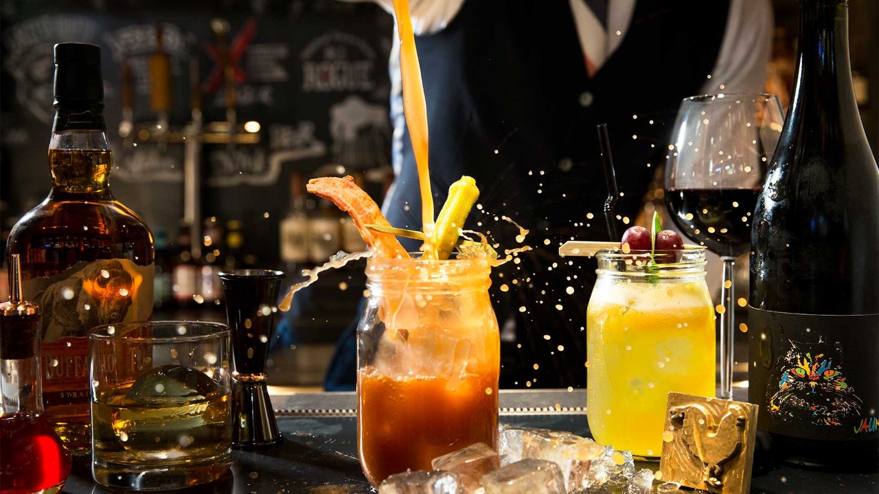 Man mixing a cup of cocktail in a waterfront bar